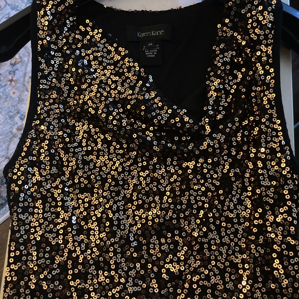 Cowl neck black and gold sleeveless blouse.